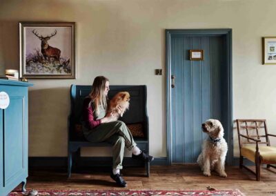 A guest sitting with a dog in the farmhouse hallway at the Country Dog Hotel