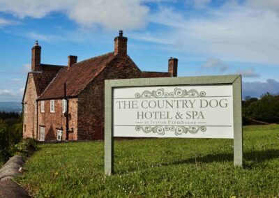 The Country Dog Hotel farmhouse with its sign in the foreground